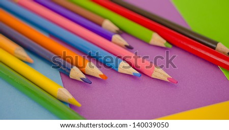 Color pencils on a green, purple, yellow and blue background