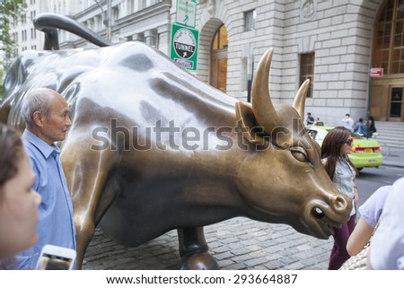 NEW YORK - May 28, 2015: Tourists posing for pictures with the Charging Bull, which is sometimes referred to as the Wall Street Bull  in the financial district of New York City.