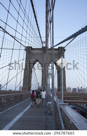 NEW YORK - May 30, 2015: People walking across the Brooklyn Bridge in New York city. Completed in 1883, it connects the boroughs of Manhattan and Brooklyn by spanning the East River.
