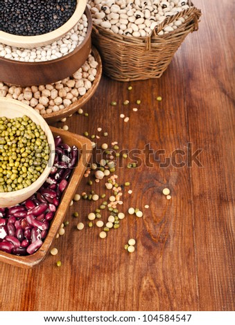 Different kinds of bean seeds, lentil, peas in dish on wooden table