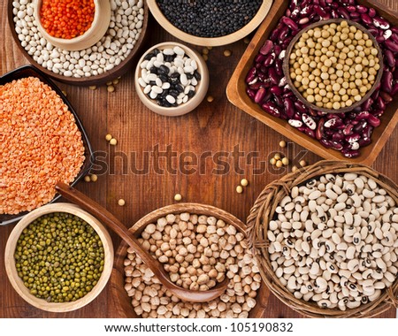 Different kinds of bean seeds, lentil, peas in dish on wooden table