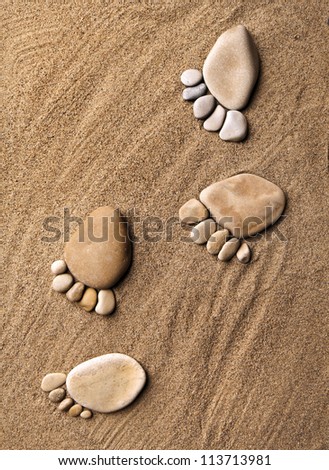 trace feet steps of a pebble stone walking on the sea sand backdrop top view surface