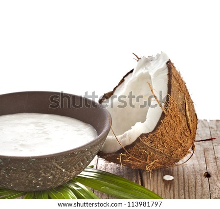 cracked coconut with milk cream in a clay bowl on wooden table