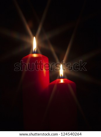 Closeup of red burning candle isolated on black background