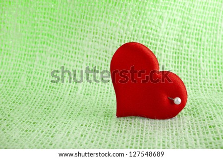 Valentine\'s day card with red heart symbol with needle on fabric sack texture background