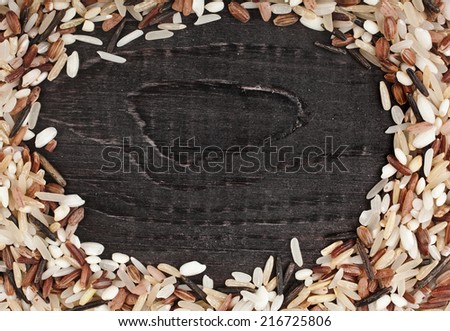 Frame made of colorful blend of rice varieties : brown rice, mixed wild rice, white (jasmine) rice in a rustic wooden surface background
