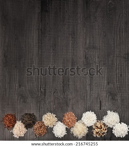 Border of colorful varieties of whole grain rice in a rustic wooden surface background