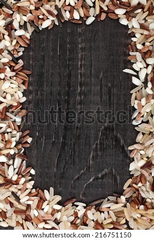 Frame made of colorful blend several varieties of whole grain rice in a rustic wooden surface background