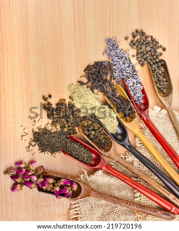 variety assortment of dry tea in scoops on wooden table background, top view