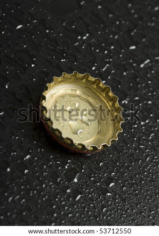 bottle cap with water droplets close up on black wet table background