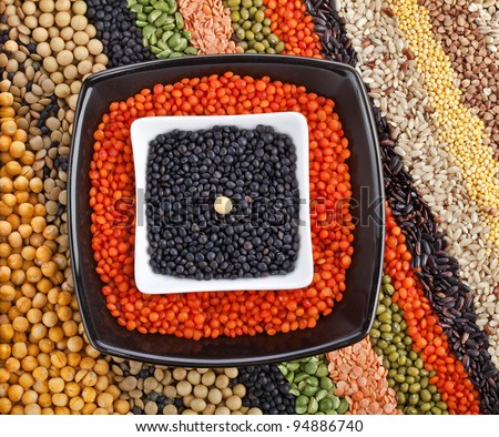 colorful striped rows of dry lentils, grain ,peas, groats , soybeans, legumes, rice, backdrop with  plate dish