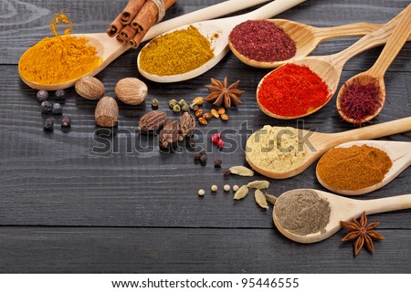 Powder spices on spoons in black wooden table background