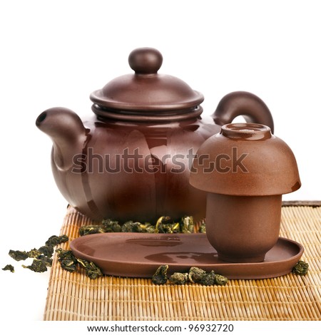 Green tea balls oolong in clay teapot and teacup isolated on white