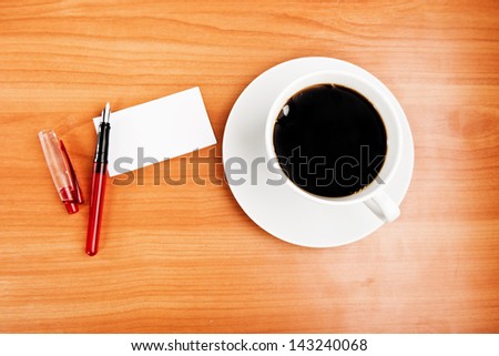 Top view of coffee cup, piece of paper and pen on the wooden table