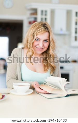 Lady reads an interesting book and drinks coffee