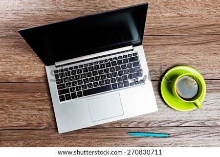 Office workplace with open laptop and cup of tea on wooden desk