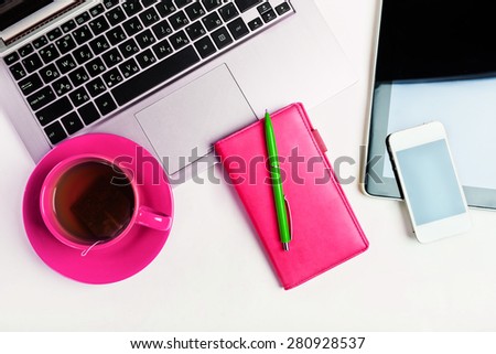 Office desk with laptop computer, tablet pc, planner, pen, mobile smartphone and cup of tea on white background