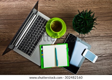 Office desk with laptop computer, tablet pc, planner, pen, mobile smartphone and cup of tea.