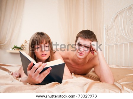 A boy trying to get some attention from his girlfriend, who\'s busy reading a book.