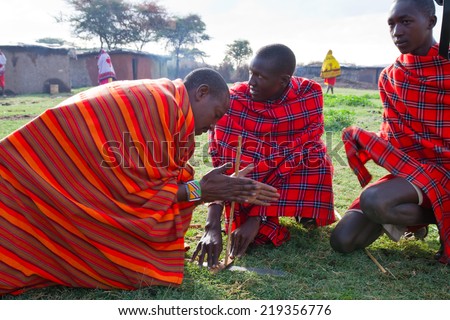 ARUSHA, TANZANIA - AUGUST 10: Masai men gathered trying to light a fire in the old way, masai people still live in the old way with traditional dress august 10, 2014 in Arusha, Tanzania