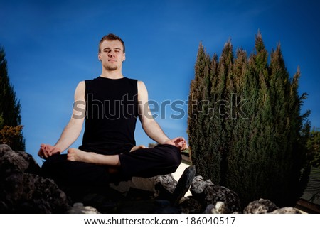 Outdoor yoga session in beautiful garden - young man meditating