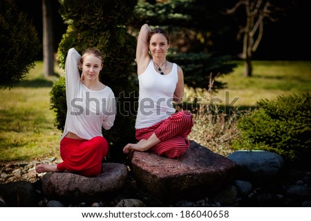Outdoor yoga session in beautiful garden - two beautiful woman exercising