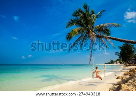 Young girl on swing on tropical island Koh Phangan in Thailand. Tourist on Chalokum beach.
