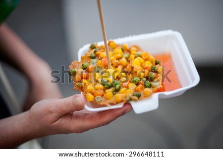 Fresh fried corn, peas and carrot fritter Tod Man Khao Pod. Traditional thai street food cuisine in hand