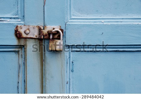 Rusty padlock on old painted wooden door