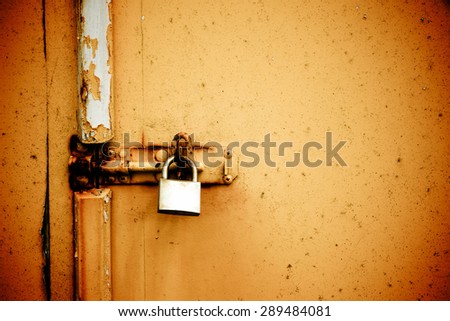 Rusty padlock on old orange painted wooden door