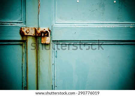 Rusty padlock on old blue painted wooden door