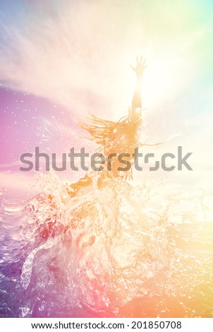 young man jumping in the water with splash and sun flare. summer beach colorful background