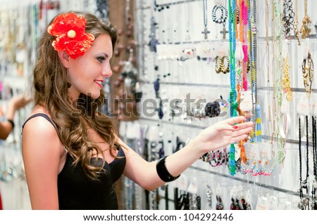 Young woman is choosing jewelry in the shop