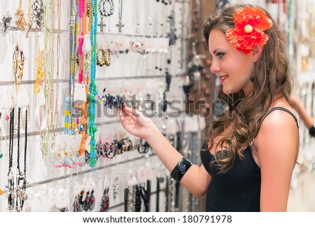 Young woman is choosing jewerly in the shop