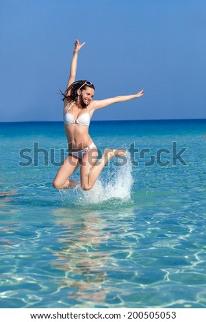 A laughing woman is jumping in water