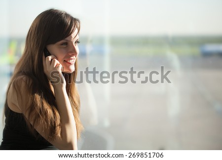 Young brunette woman is talking on mobile phone in the airport