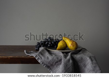 Still life with fruits. Grapes and pears on a rustic table indoors with a moody window light 商業照片 © 