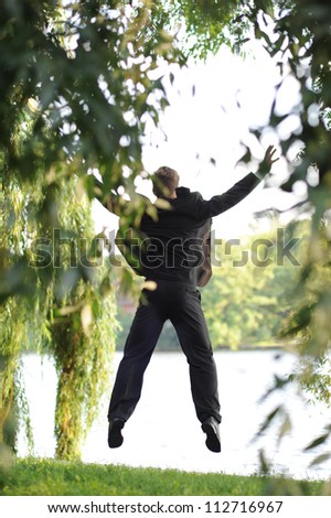 Young businessman jumping at the river.