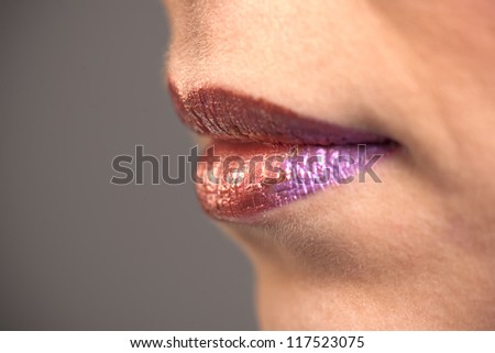 Profile view of woman\'s mouth with graphic red and purple lipstick