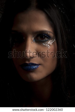 Dark portrait of beautiful woman with fantasy blue and silver makeup