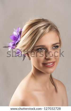 Beautiful young blonde woman with hair tied back with purple flower hair clip