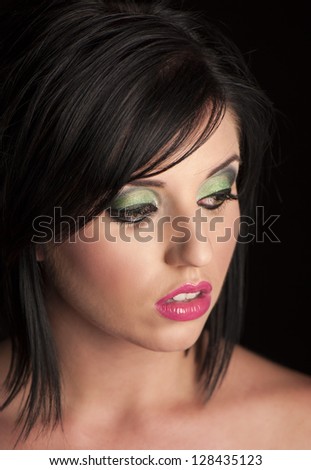 Beautiful woman with black bob hair, cerise pink lips, green eyeshadow and black eyeliner looking to the side