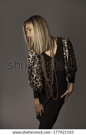 Portrait of beautiful blonde woman with gold chain necklaces and animal print dress