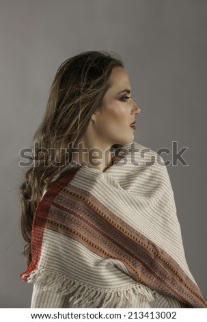 Beautiful brunette woman in profile wearing her long hair in a loose curly style and a scarf wrapped around her.