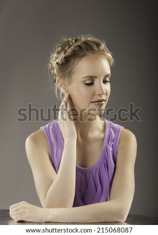 Feminine portrait in color of lovely woman wearing her blonde hair in a braided up-do, with natural makeup and a purple shirt