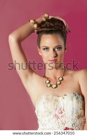 Portrait of beautiful brunette woman in spring colored makeup posing in front of bright pink background