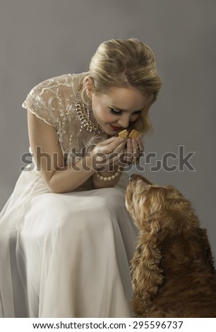 Portrait of lovely blonde girl holding a treat for her cute spaniel dog