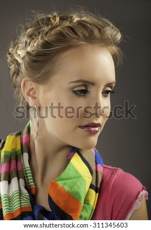 Portrait of blonde woman with romantic braided hairstyle wearing natural makeup and a bright, striped scarf