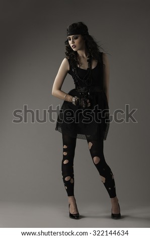 Brunette woman in grunge outfit of black, torn leggings, dress, and lace gloves,