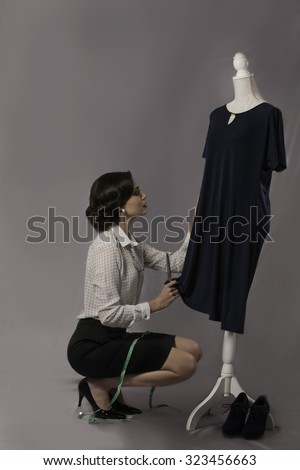 Seamstress measuring dress on dressmaker\'s dummy